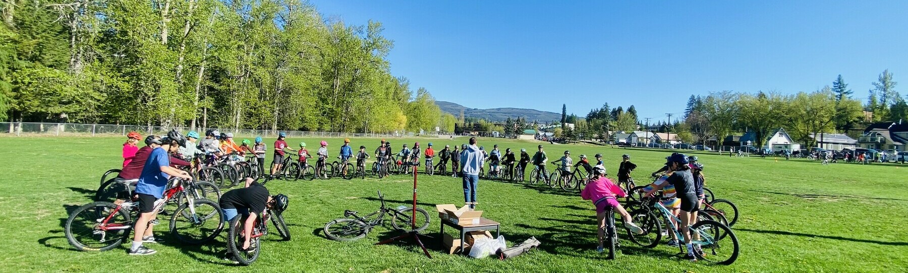 Students standing with their bikes in a circle listening to instructions during McKim Bike Rodeo
